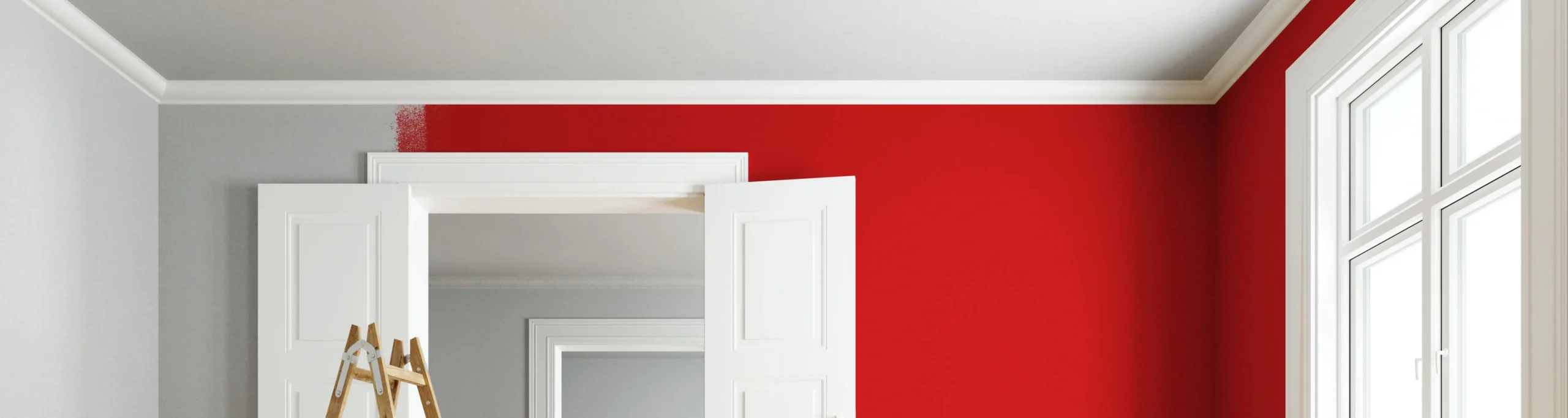 Eine Zimmerwand wird teilweise rot gestrichen, wobei eine Leiter vor einer weißen Tür steht und der Übergang von Grau zu Rot deutlich sichtbar ist.